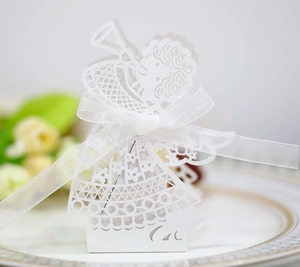 Close-up of laser-cut white angel favor box with intricate floral hollowed patterns