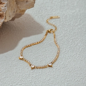 Macro detail of gold heart bracelet featuring three white heart-cut cubic zirconia stones