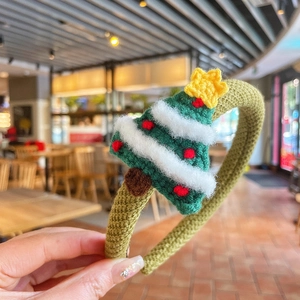 Détail d'un serre-tête arbre de Noël en tricot vert avec des décorations festives colorées