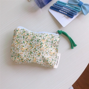 Close-up of floral cotton pouch with white zipper and green braided pull cord detail