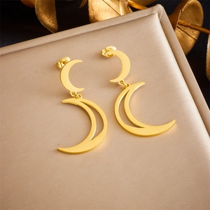 Macro view of gold plated crescent moon drop earrings displayed on a luxury textured gift box