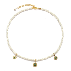 Detail of pearl necklace with gold heart and sun pendants featuring green stone inlay