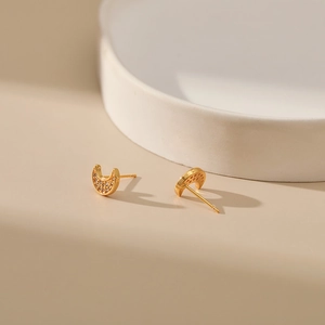 Detailed view of crescent moon stud earrings with sparkling cubic zirconia in 18K gold finish