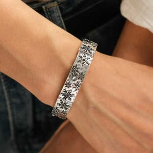 Gros plan sur un large bracelet argenté vintage avec des motifs de flocons de neige