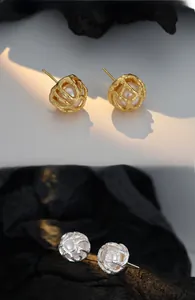 Detail of hollow metal cage earrings with freshwater pearls in gold and silver finishes