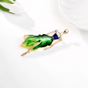 Detail of elegant dancing girl brooch with green enamel finish on a marble surface