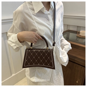 Close-up of brown quilted handbag featuring metal rivets and a woven top handle