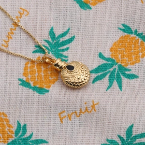 Macro shot of gold gourd pendant with fine relief patterns and a black gemstone inlay