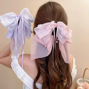 Dettaglio del fermaglio per capelli con fiocco in chiffon a fiori e ciondolo di perle