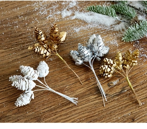 Close-up of gold, silver, and white painted natural pine cones on wood for Christmas DIY