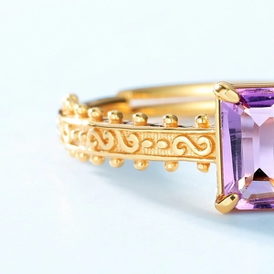Macro detail of a gold ring featuring a rectangular amethyst and intricate vintage carving
