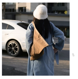 Outdoor street view of a woman wearing a blue coat and a brown minimalist shoulder bag