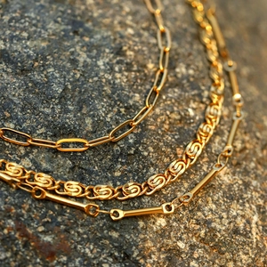 Three-layer 18k gold plated stainless steel stacked necklaces on a natural stone surface