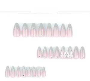 Close-up of pink ombre almond fake nails with 3D white bows and tiny rhinestones