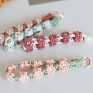 Close-up of handmade woven daisy flower phone strap with gold metal spring buckle