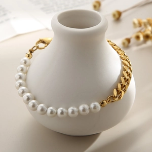 Détail d'un bracelet de perles et mailles cubaines dorées enroulé sur un vase blanc