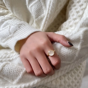Elegant gold ring featuring a round white cat-eye stone worn on a soft knit sweater
