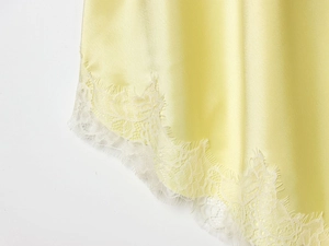 Dettaglio del tessuto in raso giallo chiaro con bordo in pizzo bianco delicato sull'orlo