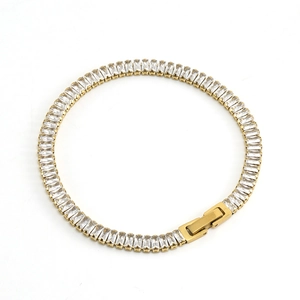 Golden tennis bracelet with rectangular cubic zirconia stones on white background