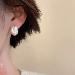 French vintage flower pearl stud earrings with gold textured edges worn by a model