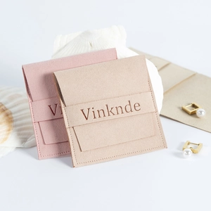 Détail de pochettes à bijoux en suédine rose et beige avec logo embossé et perles