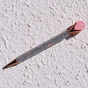 Detailed macro view of rainbow rhinestone pen with rose gold metal and a large pink crystal top