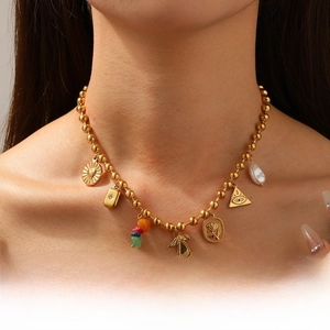 Detail of gold-plated ball chain necklace featuring cherry skull and pearl charms