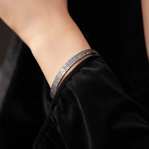 Close-up of silver metal bangle featuring traditional Chinese characters and auspicious patterns