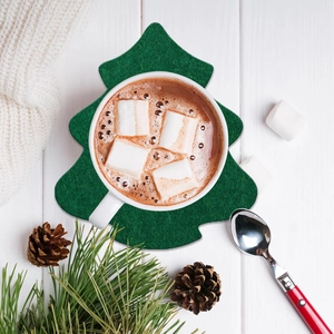 Christmas tree shaped green felt coasters for drinks on white wood background