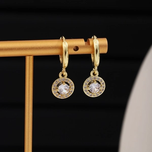 Macro view of gold hoop earrings featuring a halo drop pendant with sparkling center stone