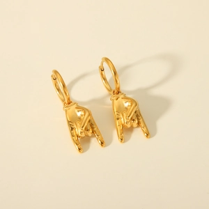 Detail of gold rock gesture earrings with high-quality polished metallic finish