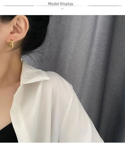Close-up of gold geometric layered earrings worn by a model for size and style detail