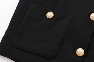 Detail of black fabric texture with three textured gold metal buttons on a short jacket