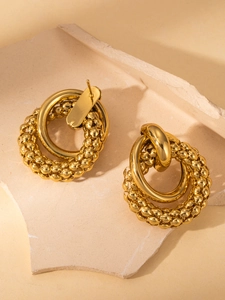 Detailed macro view of gold-toned hoop earrings with textured braided and polished bands