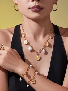 Detail view of gold coin pendant necklace and baroque pearl bracelet on model