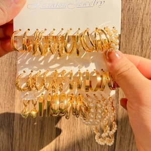 Detail view of gold vintage geometric earring set with pearls and heart charms on a card