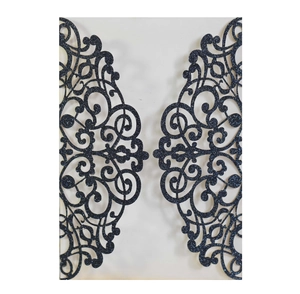 Macro detail of black glitter cardstock with laser-cut vine patterns on a wedding invitation