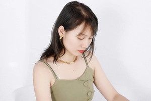Detail of gold Cuban chain necklace and rectangular earrings set on a female model