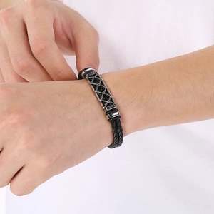 Close-up of double-layer black braided leather bracelet with silver hollow pattern clasp