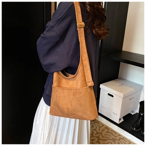 Detail view of brown suede crossbody bucket bag with functional front pockets