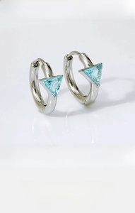 Close-up of titanium steel hoop earrings featuring light blue triangular gemstones