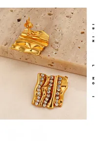 Détail macro de boucles d'oreilles dorées ondulées avec quatre rangées de zircons