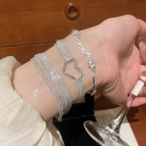 Close-up of triple layered silver bracelets with heart charm and zircon stones on a wrist