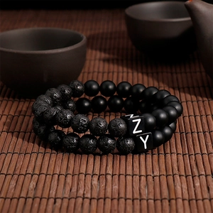 Detail of matte agate and volcanic stone bracelet set with letter beads on bamboo mat