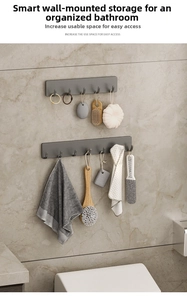 Detail view of wall-mounted gun grey matte hooks on marble wall in bathroom setting