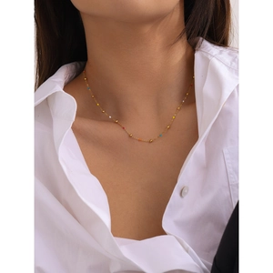 Golden stainless steel necklace with colorful small beads worn by a model in soft light