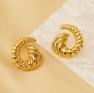 Detailed close-up of golden croissant twist earrings on elegant marble background