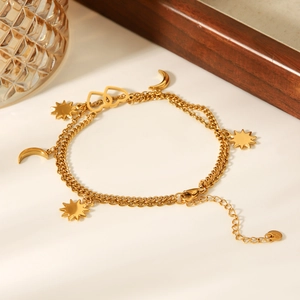 Macro detail of 18K gold stainless steel anklet with moon star and double heart charms