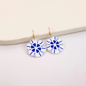 Close-up of blue and white floral acrylic earrings with elegant golden metal hooks