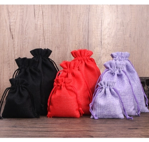 Linen drawstring jewelry pouches in black, red, and purple on a wood surface